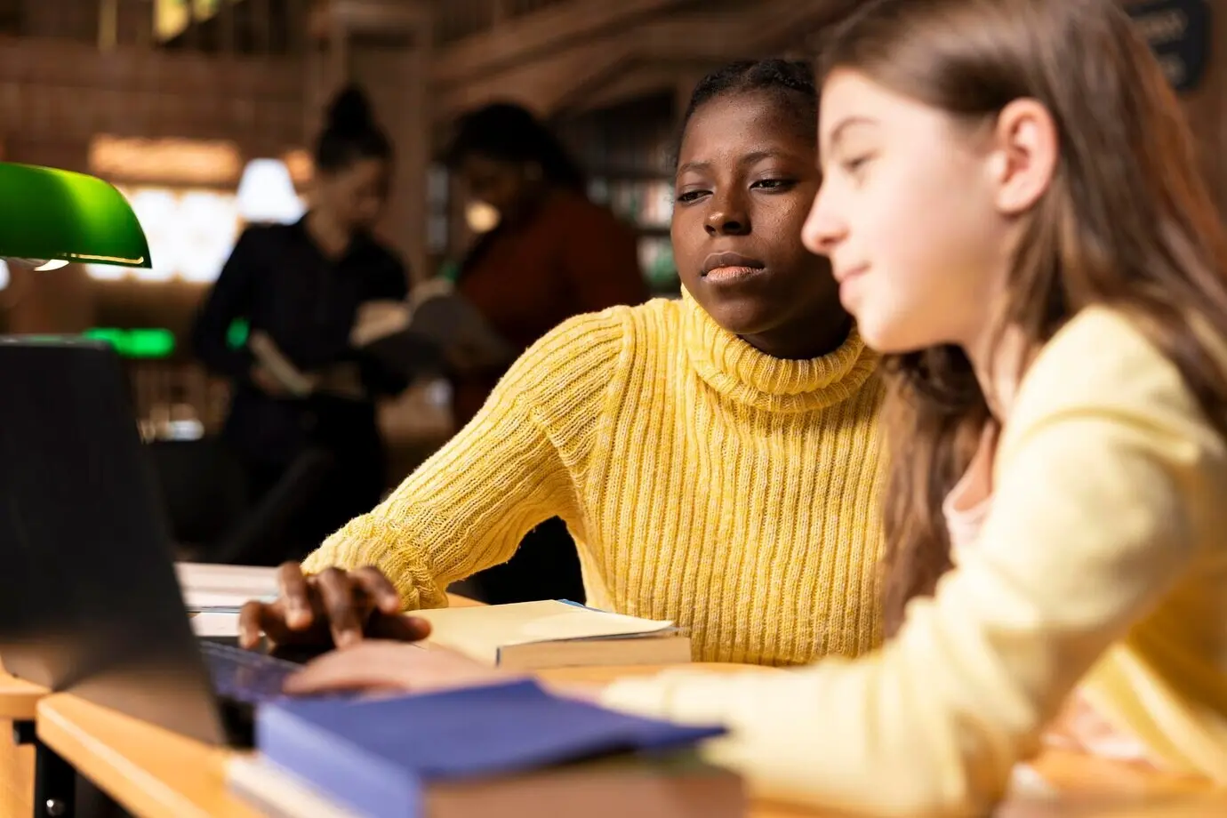 Junge Teenagerinnen am Lernschreibtisch, die an virtuellem Webinar-Unterricht teilnehmen.